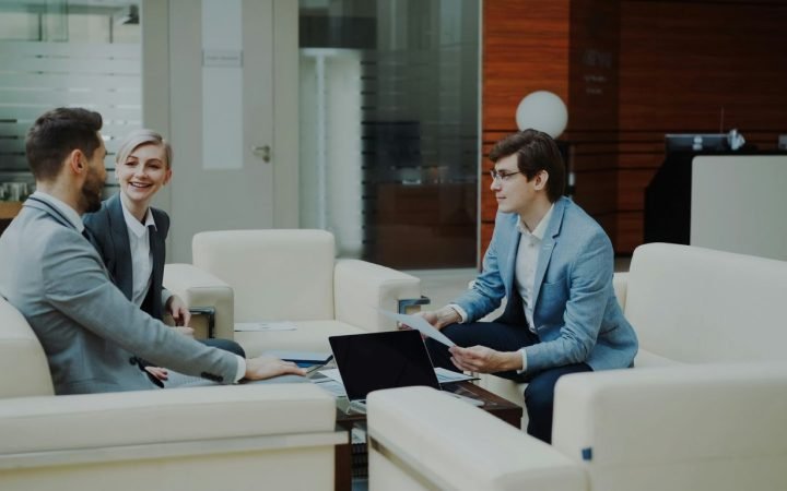 Three professionals in a modern office lounge.