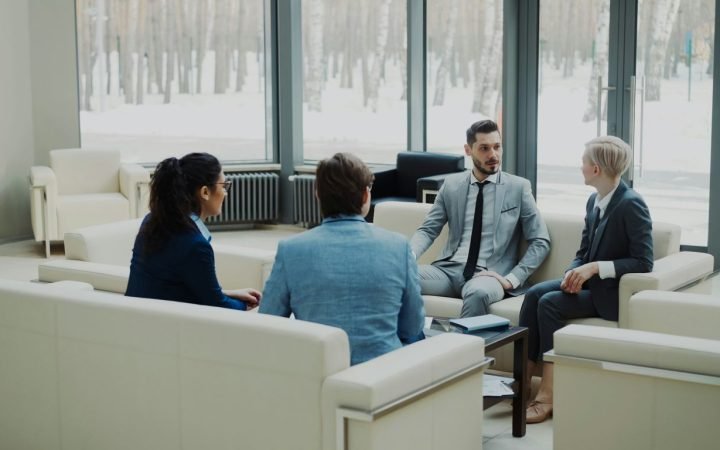Four professionals in a modern office meeting space.