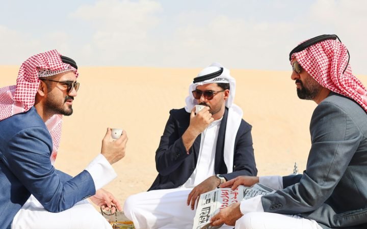 A group of men sitting on top of a sandy beach